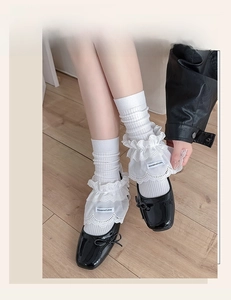 Detail view of white lace ruffled leg warmers paired with black Mary Jane shoes