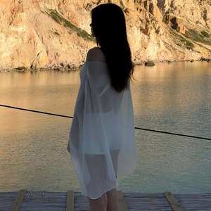 Detail of sheer white chiffon cover-up back view on a beach with soft natural lighting
