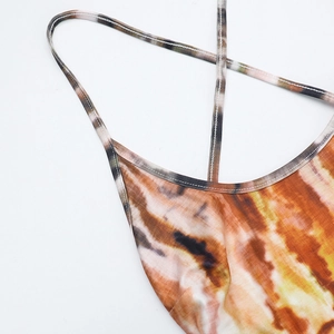 Dettaglio macro del tessuto tie-dye arancione con spalline sottili e finitura del collo