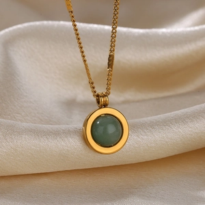 Close-up of a double-layered gold chain necklace with a green gemstone sunflower pendant