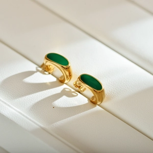 Macro view of gold-plated geometric earrings with vintage green enamel inlay
