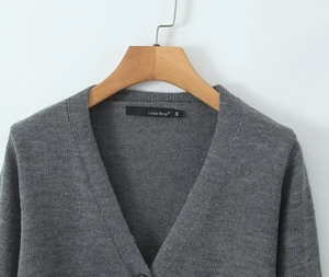 Détail d'un cardigan en maille gris foncé avec col en V et étiquette de marque