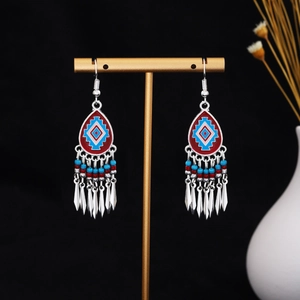 Detailed shot of ethnic tribal earrings with red and blue enamel drops and silver tassels