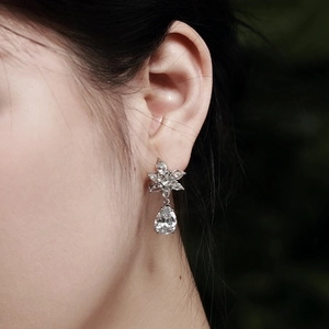 Close-up of 925 silver flower stud earrings with pear-shaped drops and sparkling zircons