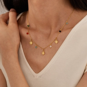 Elegant gold stainless steel necklace with star charms and colorful beads on a model