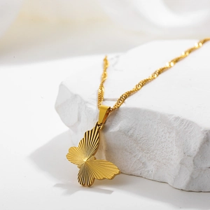 Macro view of golden butterfly pendant with radial texture on a white stone base