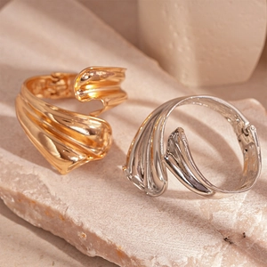 Chic irregular wavy metal bangles in gold and silver finish on stone background