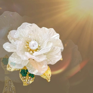Macro shot of pearl camellia brooch with golden leaves and sparkling rhinestones