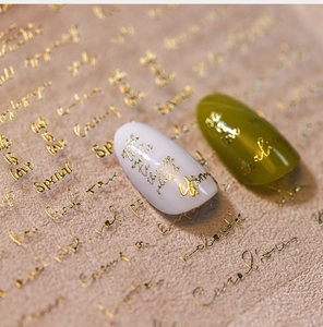 Detail of 3D embossed gold lettering on creamy white and olive green nail stickers