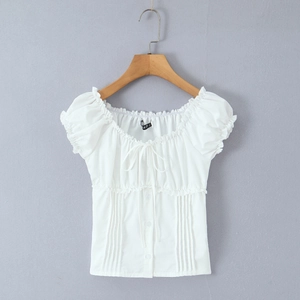 Detail of white square neck blouse featuring ruffled edges and a front bow tie design
