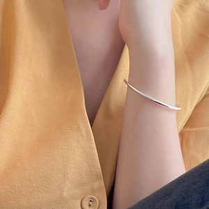 Close-up of minimalist S925 sterling silver thin geometric open bangle worn by a model