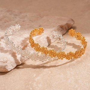 Set of gold and silver open daisy flower bracelets on a natural stone background