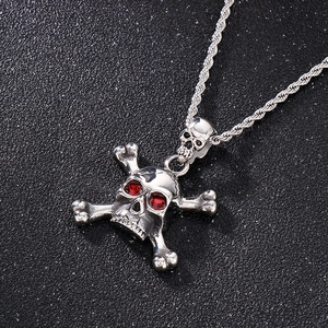 Detailed close-up of hip-hop silver skull pendant with red rhinestone eyes and twist chain