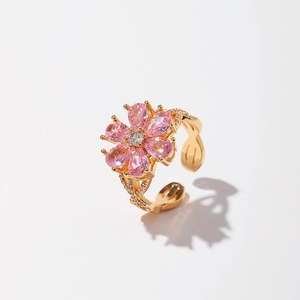 Detailed close-up of a flower-shaped gold-plated ring with pink zircon petals and crystals