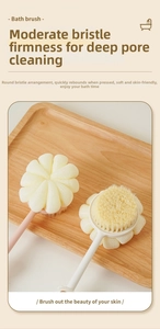 Close-up of long handle bath brush with pink mesh loofah and soft bristles on wooden tray