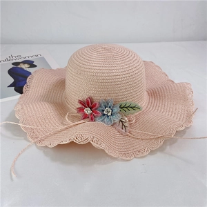 Detail of pink straw sun hat with 3D floral accents and wavy openwork brim