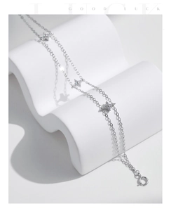 Detail of silver S925 clover bracelet with sparkling zircons on a white display