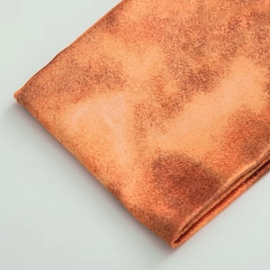 Macro shot of orange mottled knit fabric texture with detailed weave pattern
