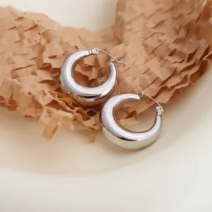 Close-up of polished C-shaped hoop earrings with bright silver finish on paper background