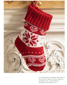 Detail of red knitted Christmas stocking with white snowflakes hanging on white fireplace
