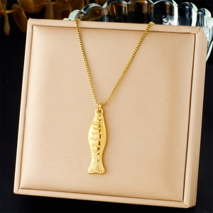 Detail of a 3D gold fish pendant on a square box chain in a champagne jewelry box