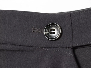 Detailed close-up of dark woven suit fabric with marble-textured button and neat stitching