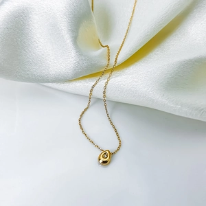 Macro detail of gold waterdrop necklace with sparkling zircon on white silk background