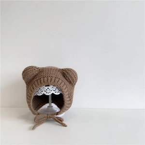 Detail of coffee brown baby knit hat with bear ears and ear flaps on white display stand