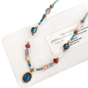Collier ethnique avec perles colorées et pendentif en pierre bleue sur fond blanc
