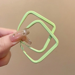 Detail view of light green double-layer diamond shaped earrings held by hand
