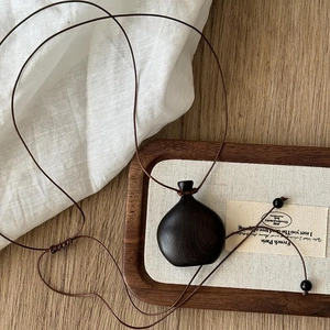 Detail of retro wooden vase pendant on brown wax cord with vintage ethnic style design