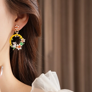Détail de boucles d'oreilles vintage lapin et fleurs portées sur fond de tissu brun