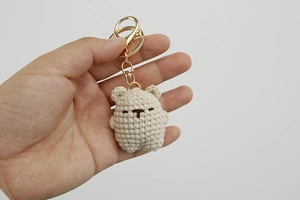 Detailed view of a handmade crochet teddy bear keychain with gold metal clasp and chain
