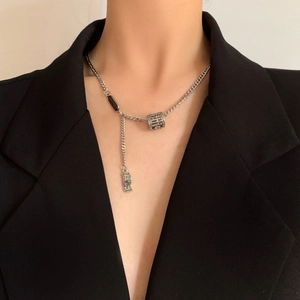 Detail of silver abacus and coin pendant Y-necklace worn on a black blazer