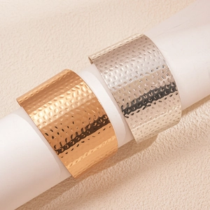 Detailed close-up of wide hammered metal cuff bracelet in gold and silver finishes