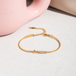 Detailed macro view of 18K gold-plated stainless steel bracelet with heart charm and small diamonds
