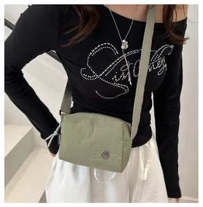 Dettaglio della borsa a tracolla in nylon verde oliva con logo M in metallo e etichetta