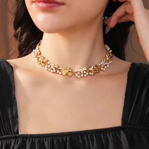 Detail of vintage gold leaf necklace with white pearls worn on a model's collarbone