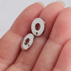 Close-up of two polished stainless steel round pendants with dual holes for DIY jewelry