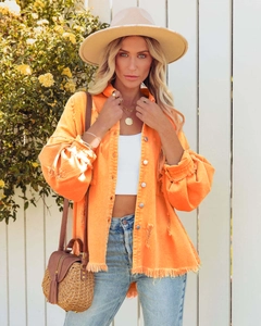 Detail view of the orange denim jacket featuring puff sleeves and frayed hem edge design