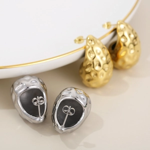 Modern 18K gold and silver teardrop earrings with hammered texture on a white plate