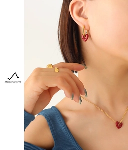 Detail view of a model wearing a stainless steel gold heart necklace and earring jewelry set