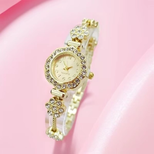 Detail of flower-shaped golden quartz watch with rhinestone accents and metal chain strap