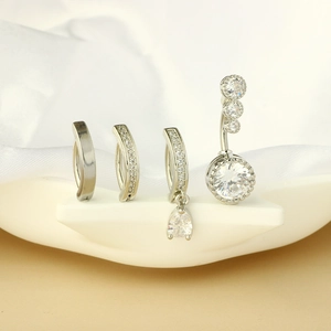 Sleek stainless steel belly rings with sparkling zircon studs on a white silk background