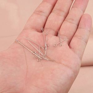 Silver stainless steel eye pins for jewelry making held in palm for size scale