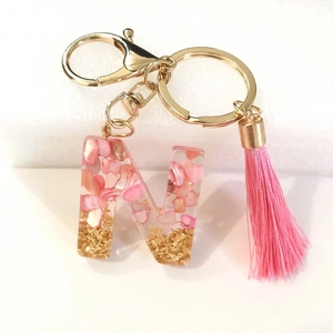 Close-up of letter N keychain with pink shell fragments and gold foil in resin