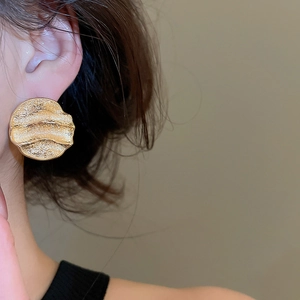 Détail de grandes boucles d'oreilles dorées avec texture martelée vintage sur mannequin