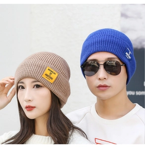 Detail view of knit beanie hats in light brown and royal blue with woven logo patch