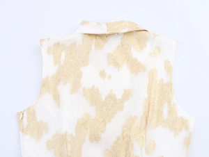 Détail d'une robe blanche à texture dorée, col à revers et fermeture éclair invisible