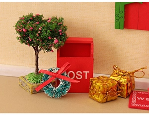 Miniature Christmas dollhouse scene with red mailbox, pink tree, and tiny gift boxes